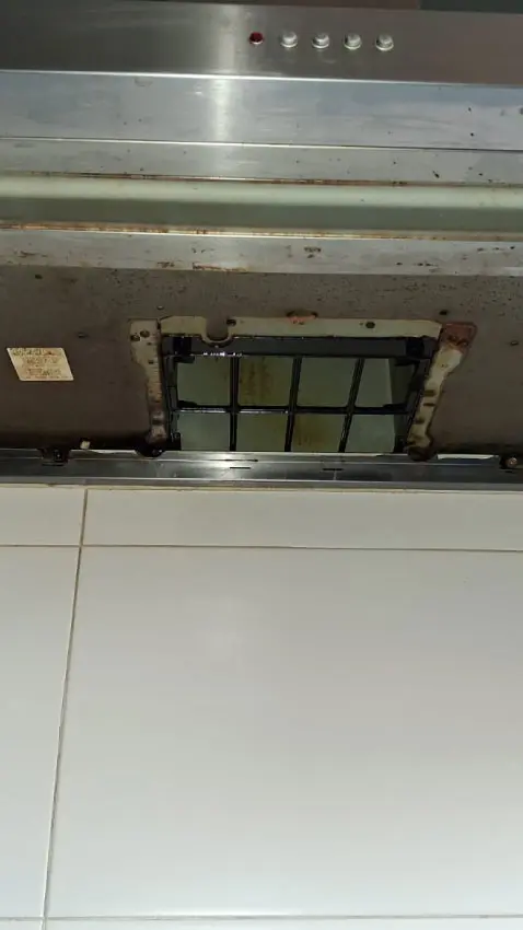 Primer plano de unos filtros metálicos de extractor de cocina saturados de grasa acumulada.