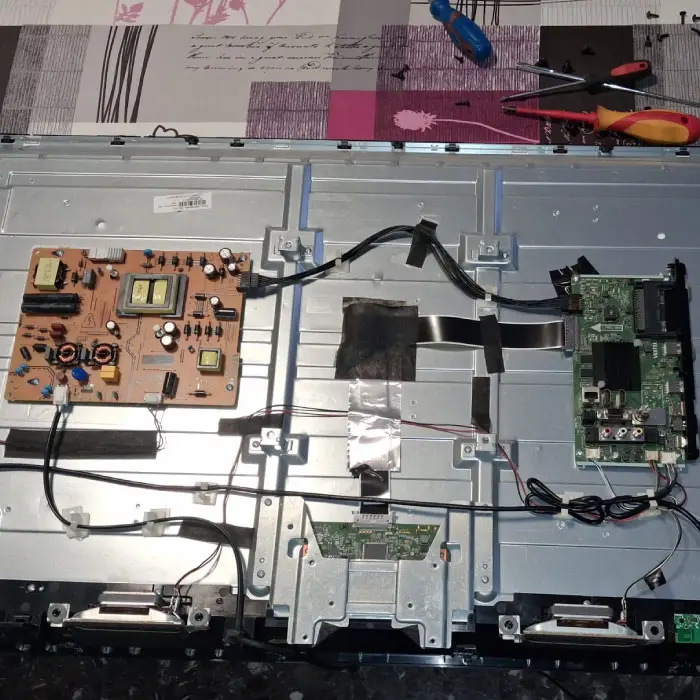 Técnico especialista desarmando el panel de un televisor con la pantalla negra para reparar diodos LED en Barcelona.