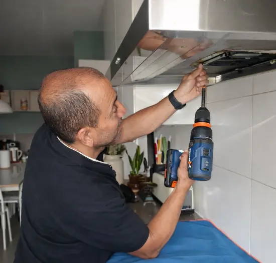 Especialista instalando el motor de extracción y los filtros de una campana de cocina.