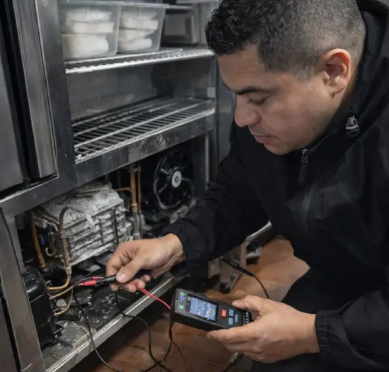 Especialista en frío industrial verificando el termostato y ventiladores de una cámara frigorífica.