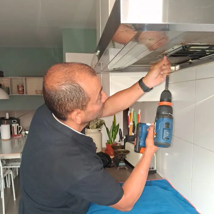 Técnico especializado de Electro González con su uniforme ajustando el chasis de una campana de cocina.